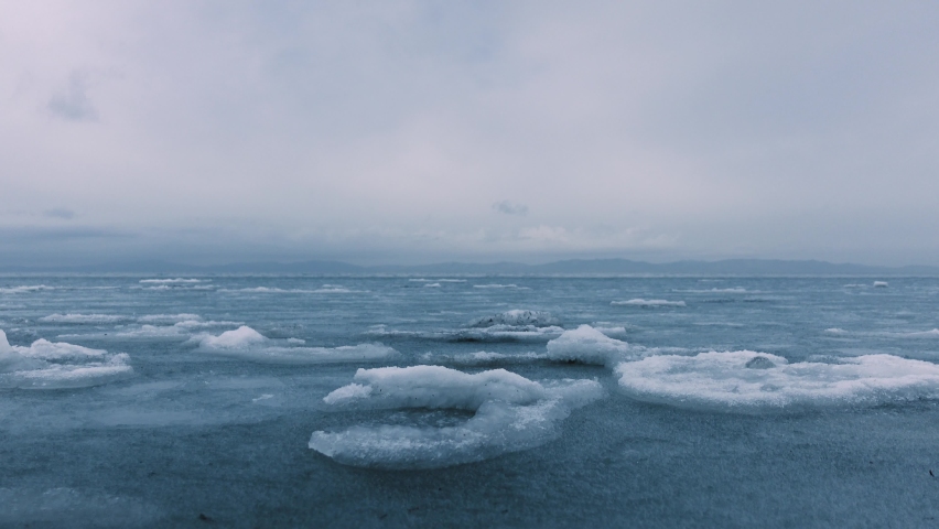 Frozen sea. The north Sea is not completely frozen yet and the ice floes are swaying on the waves. Gloomy weather on the horizon. Royalty-Free Stock Footage #1084213789