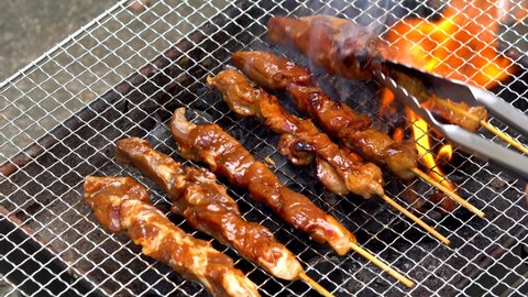 flipping pork barbecue; a famous Filipino street food 