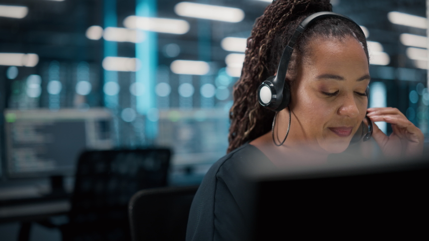 Call Center Office: Portrait of Friendly African American Female Technical Customer Support Specialist Talking on a Headset, uses Computer. Client Experience Officer Helps Online via Video Conference Royalty-Free Stock Footage #1084218118