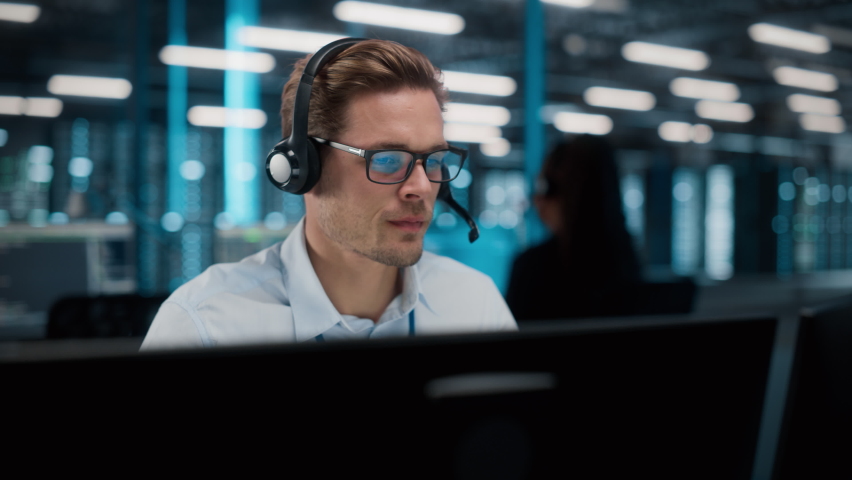 Call Center Office: Portrait of Friendly Caucasian Male Technical Customer Support Specialist Talking on a Headset, uses Computer. Client Experience Officer Helps Online via Video Conference Royalty-Free Stock Footage #1084218136