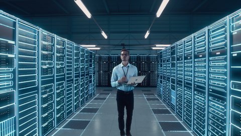 Futuristic Animated Concept: Big Data Center Chief Technology Officer Using Laptop Standing In Warehouse, Activates Servers, Information Digitalization Starts. SAAS, Cloud Computing, Web Service