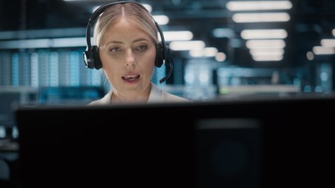Call Center Office: Portrait of Friendly Caucasian Female Technical Customer Support Specialist Talking on a Headset, uses Computer. Client Experience Officer Helps Online via Video Conference