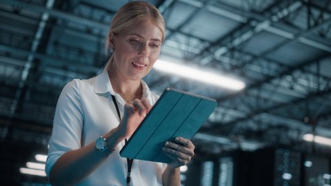 Caucasian Female IT Specialist Using Tablet Computer, Walk Through Big Warehouse Data Center. System Administrator working with Computing SAAS, Cloud Services Server. e-Business Digital Entrepreneur