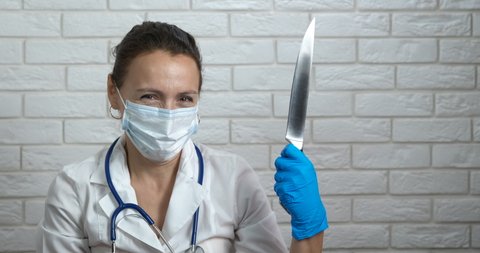 Operation knife for doctor. A serious doctor in white uniform hold a big knife in her hand.