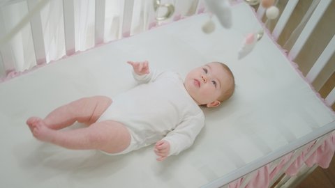 Very excited baby girl enjoy the time in her baby cot alone she moving with her cute legs and looking at cot toys