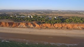 Aerial video of the beautiful Portuguese southern beaches of Falesia. Sandy mountains tourists on vacation.