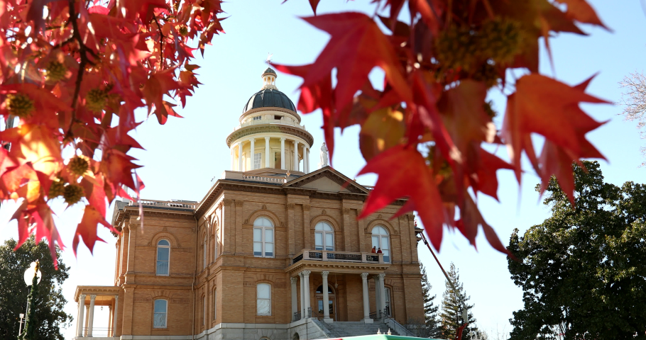 Selective focus view of liquid amber leaves framing the historic courthouse of Auburn, California, USA.