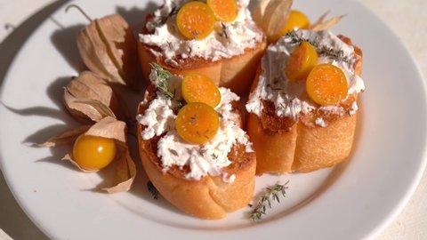 Ricotta bruschetta topped with cape gooseberries rotated on a white plate. Ripe fresh Physalis plant, yellow berry. Cape gooseberry, Goldenberry. Tropical fruit and food for health concept.