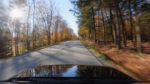 Driving black car on Vermont curvy road in Autumn season. Colorful trees by the road side. POV