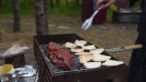 Man roasts a juicy kebab barbecue on the grill in the forest. Cook grills meat outdoors.