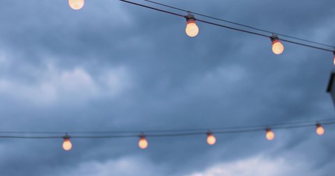 the rows of party light bulb strings over the cloudy sky background