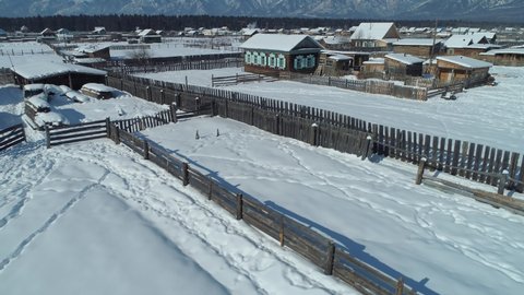 Drone upwards flight, old Russia Buryatia village historical typical wooden carved houses winter snow covered roofs. Epic Arshan mountains natural park reserve Authentic settlement. Open space. Stock