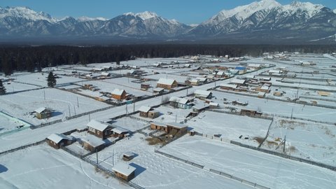 Aerial flight above authentic old wooden houses village Buryatia Russia Siberia. Frosty winter snowy mountains of Arshan. Tourist attraction. Epic countryside rural natural landscape. National park