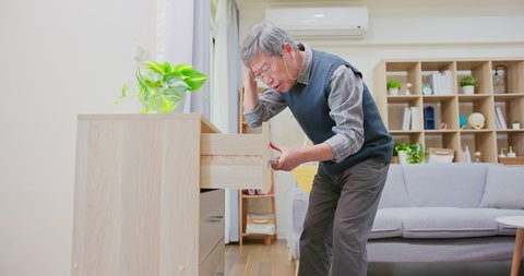Amnesia and memory loss - asian older man wearing reading glasses is through all the drawers and he forgot something