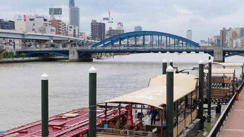 Tokyo, Japan - October 24, 2019: Video of Houseboat (yakatabune) for the chartered cruise on the Sumida River and blue tied-arch Komagata bridge connecting Komagata with Higashi-komagata.