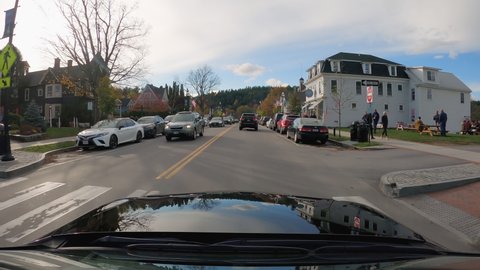 Stowe, United States - CIRCA OCTOBER 2021: Driving a car on main street in Stowe, charming small ski town in Vermont, New England. Sunny day with clouds, autumn season