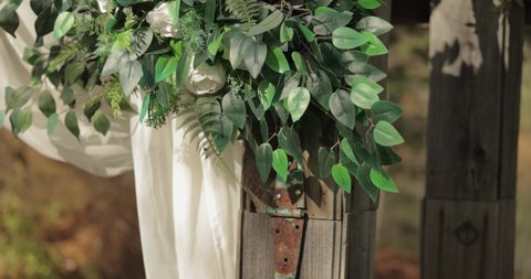Beautiful white rose floral arrangement mounted on a rustic wedding arch at a wedding ceremony at Bean Town Ranch.
