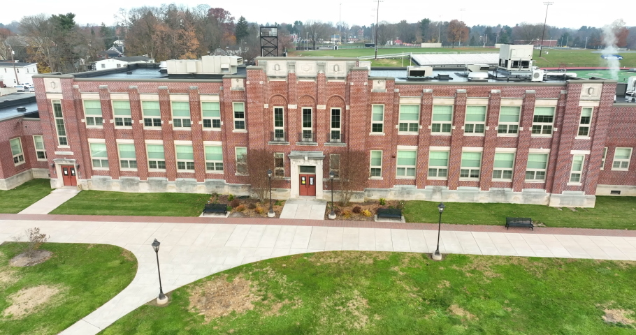 Aerial establishing shot of two story brick school on college university campus. Old fashioned traditional building. Royalty-Free Stock Footage #1084246273