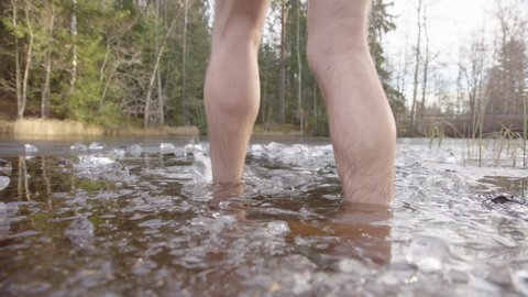CLOSEUP of ice bathers feet entering the icy water of a lake