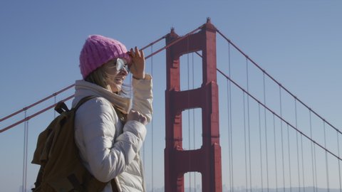 Young woman on road trip or urban city adventure. Millennial traveller visiting scenic Golden Gate Bridge observation point and enjoying view on cool sunny day. Modern independent woman concept travel