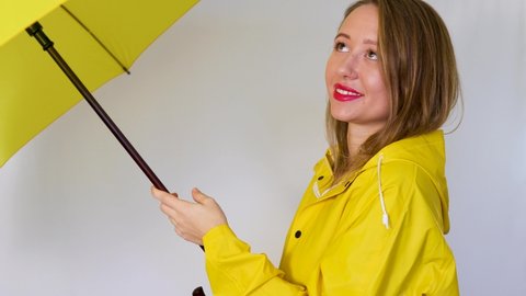 The girl in the yellow raincoat folds the umbrella. Isolated on white background.