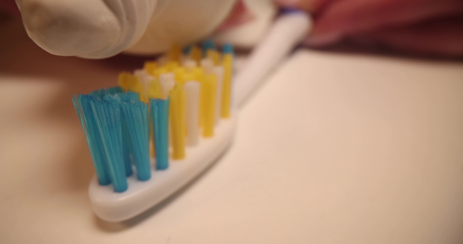 White toothpaste lying on toothbrush closeup 4k movie slow motion