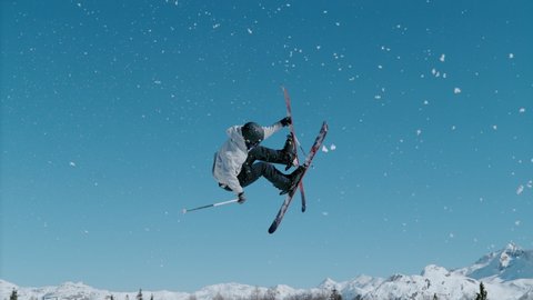 SLOW MOTION, CLOSE UP: Male freestyle skier takes off a kicker and does a challenging 360 grab while riding in the snowpark of Vogel, Slovenia. Spectacular shot of a man doing an extreme skiing trick.