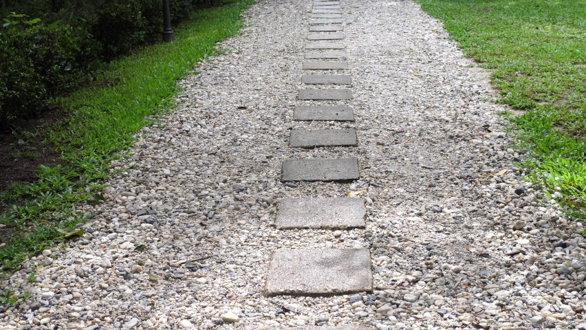 Stone walkway in a marvelous flowered botanical garden, back zoom