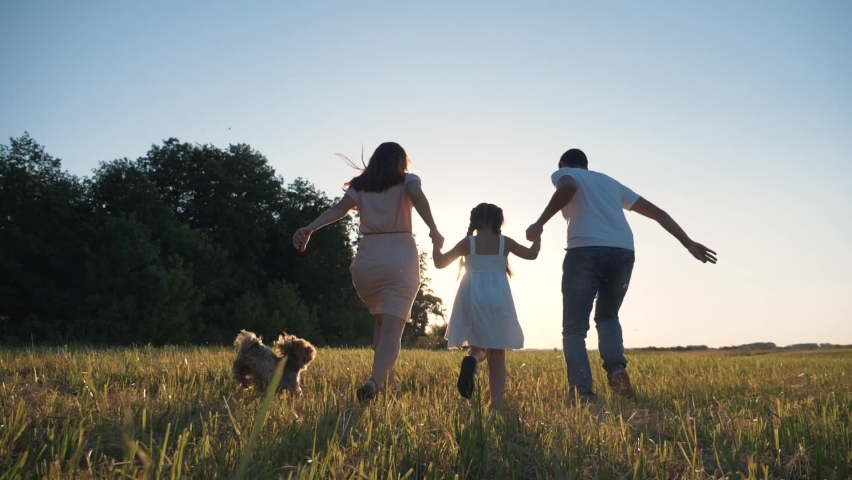 Happy family in park at sunset with pet. family has fun with child. Parents hold child by hands. Helping hand of parents. Walking happy family with pet in park at sunset. Family vacation with a dog Royalty-Free Stock Footage #1084264603