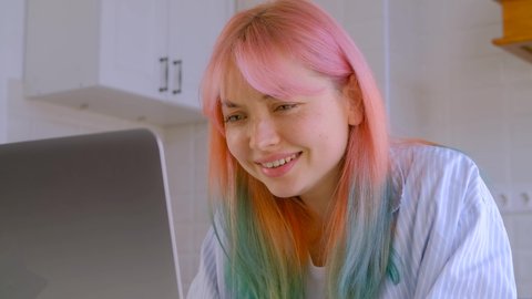 Freelancer girl with dyed hair typing text on laptop computer with confused facial expression. Young creative professional doing free lance work from home on lockdown