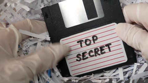 Top secret information on retro vintage floppy disk magnetic computer among shredder paper, thief information concept, closeup