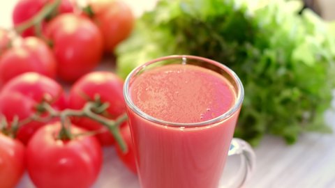 tomato juice with sprig of tomatoes on background. Tomato juice is poured into a glass.