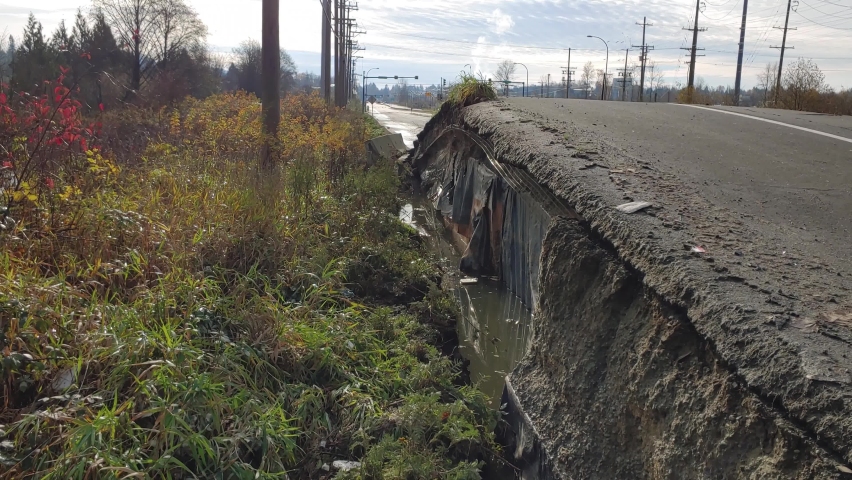 Damaged road from water flowing underneath in a flood at Abbotsford, BC, Canada - dolly shot