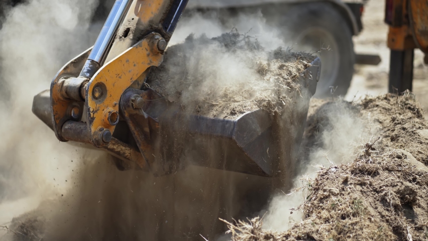 Close up of industrial excavator loading soil material on a highway construction site into a dumper truck, slow motion Royalty-Free Stock Footage #1084274932