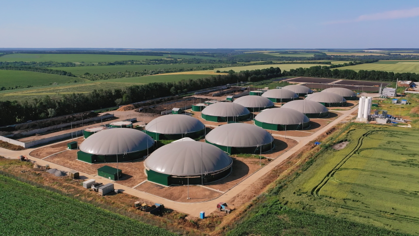 Biogas complex in the green plantations. Biogas storage tanks from the air perspective. Beautiful nature scenery at the backdrop. | Shutterstock HD Video #1084277050