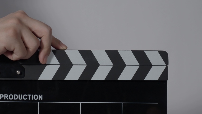 Clapper board. Close up hand and film making clapperboard isolated on background studio. Movie or video production concept. Clappers board Shuts. Film crew holds film slate in hand for video recording | Shutterstock HD Video #1084277176