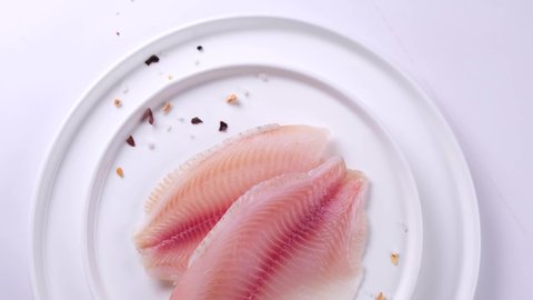 Fillet of telapia fish or other sea fish close-up on a plate with spices and salt