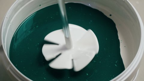 Mixing green and white paint top view. Texture of acrylic color mixture close-up. Painting walls, renovation concept. 