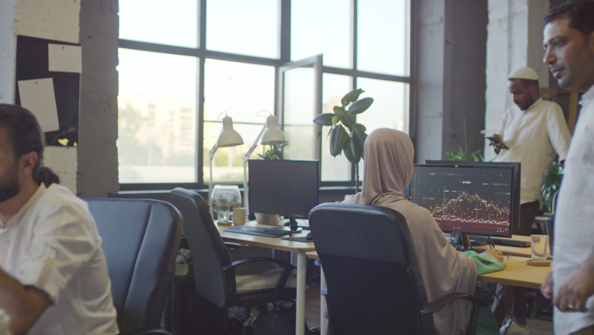 Medium long of Middle Eastern man approaching his male Biracial colleague who sitting at desk in office, working on computer, coworkers talking at daytime Royalty-Free Stock Footage #1084285825