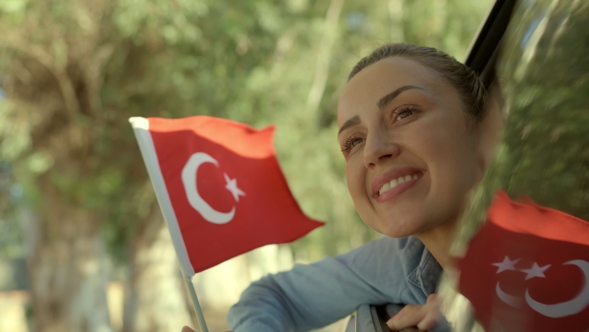 Slow Motion: Beautiful young woman waving Turkish flag from a car window.Travel Concept. Young woman coming out of car window smiling and waving Turkish flag. Celebration concept.  | Shutterstock HD Video #1084291303