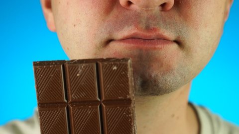 Man biting and eating chocolate bar. Close up of lower half male face, eating sweet food