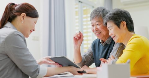 Elderly asian couple are buying house with real estate agent and sign the contract on tablet pc