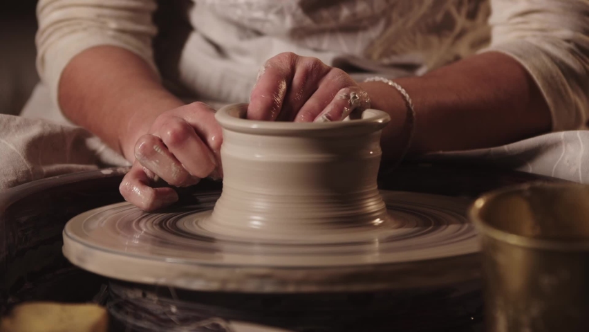 Pottery workshop - female hands pulling the clay in oblong shape