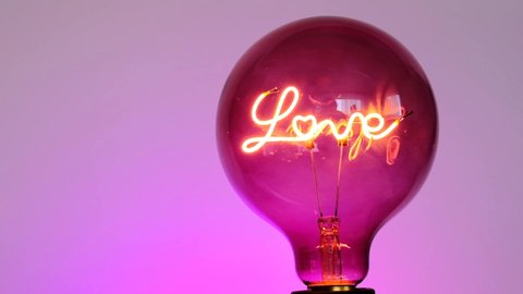 Love concept. Valentine's Day. Love light bulb.Turning on a light bulb.purple Light bulb  with the inscription love on a purple background. Love and relationship symbol.Valentine's Day.
