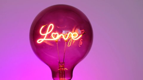 Valentine's Day. Love light bulb.Turning on a light bulb.purple Light bulb  with the inscription love on a purple background. Love and relationship symbol.