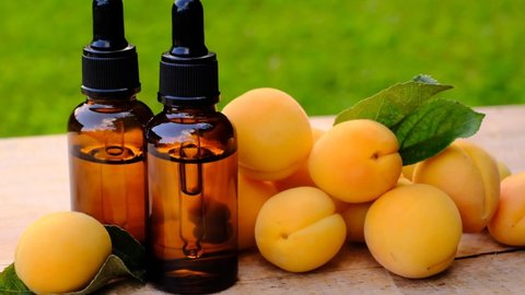 Apricot oil  bottle and  apricots fruits on a wooden table. Apricot kernel oil. Organic natural bio oil.
