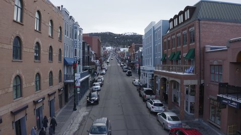 Aerial drone view of Main Street, Park City, Utah, USA which is a shopping high-street with cars parked on both sides through mountain city on a cold winter evening.