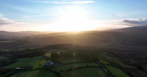 Roundwood, Wicklow, Ireland. December 2021 Drone slowly pushes west above the evening farmland with a golden winter sunset in the distance.