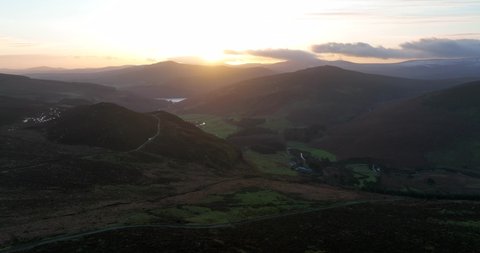 Lough Tay, Wicklow, Ireland. December 2021 Drone tracks west while facing towards Roundwood and Lough Dan with a golden winter sunset in the distance.
