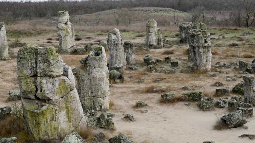 Solitary woman walks slowly among ancient rnagnificent natural rock formations